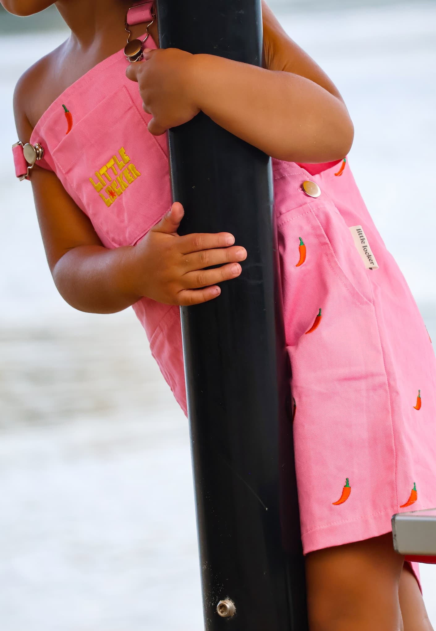 Pink girls summer overalls with chilli pepper embroidery and yellow embroidered Little Locker logo.