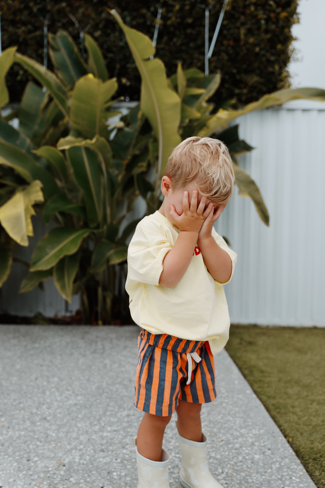 A toddler boy wearing Little Locker's Zinger shorts, in Navy/Orange. Featuring striped corduroy and an elastic waistband and drawstring.