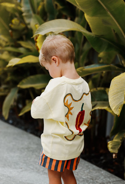 A stylish toddler wears Little Locker's "MOOD: spicy" yellow graphic t-shirt with striped corduroy shorts for a fun and modern look.