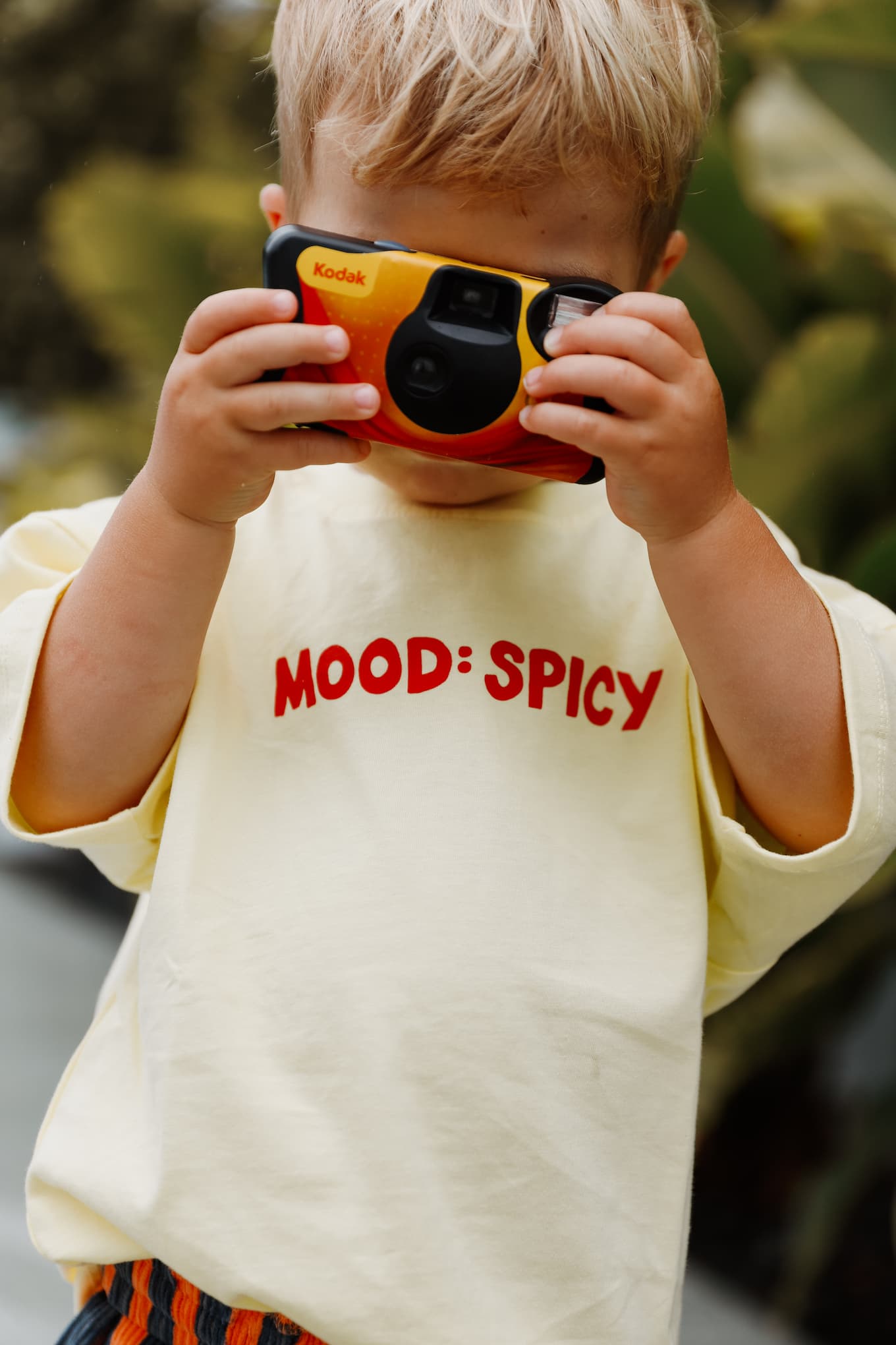 A stylish toddler pairs Little Locker's "MOOD: spicy" graphic t-shirt with striped corduroy shorts for a fun and modern look.