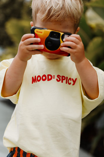 A stylish toddler pairs Little Locker's "MOOD: spicy" graphic t-shirt with striped corduroy shorts for a fun and modern look.