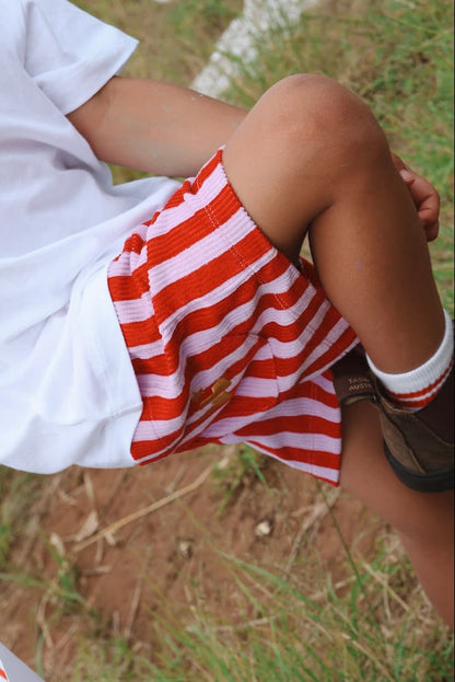 Child wearing a 'Mood Spicy' shirt and red and purple striped corduroy 'Zinger' shorts.